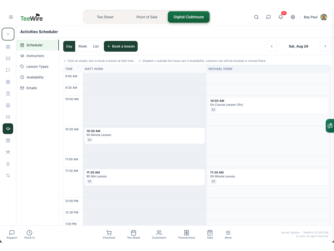 The Activities Scheduler in TeeWire on a single day, with one column per instructor side by side and the day running down the left in half hour rows. Four booked lessons sit in the grid, each card carrying its start time, the lesson type by name, and how many of its seats are taken. Above the grid are the day, week and list views, a Book a lesson action and the date being viewed. A note explains that clicking an empty slot books a lesson at that time, and that shaded hours fall outside the instructor availability but can still be booked into. The left rail lists Scheduler, Instructors, Lesson Types, Availability and Emails.